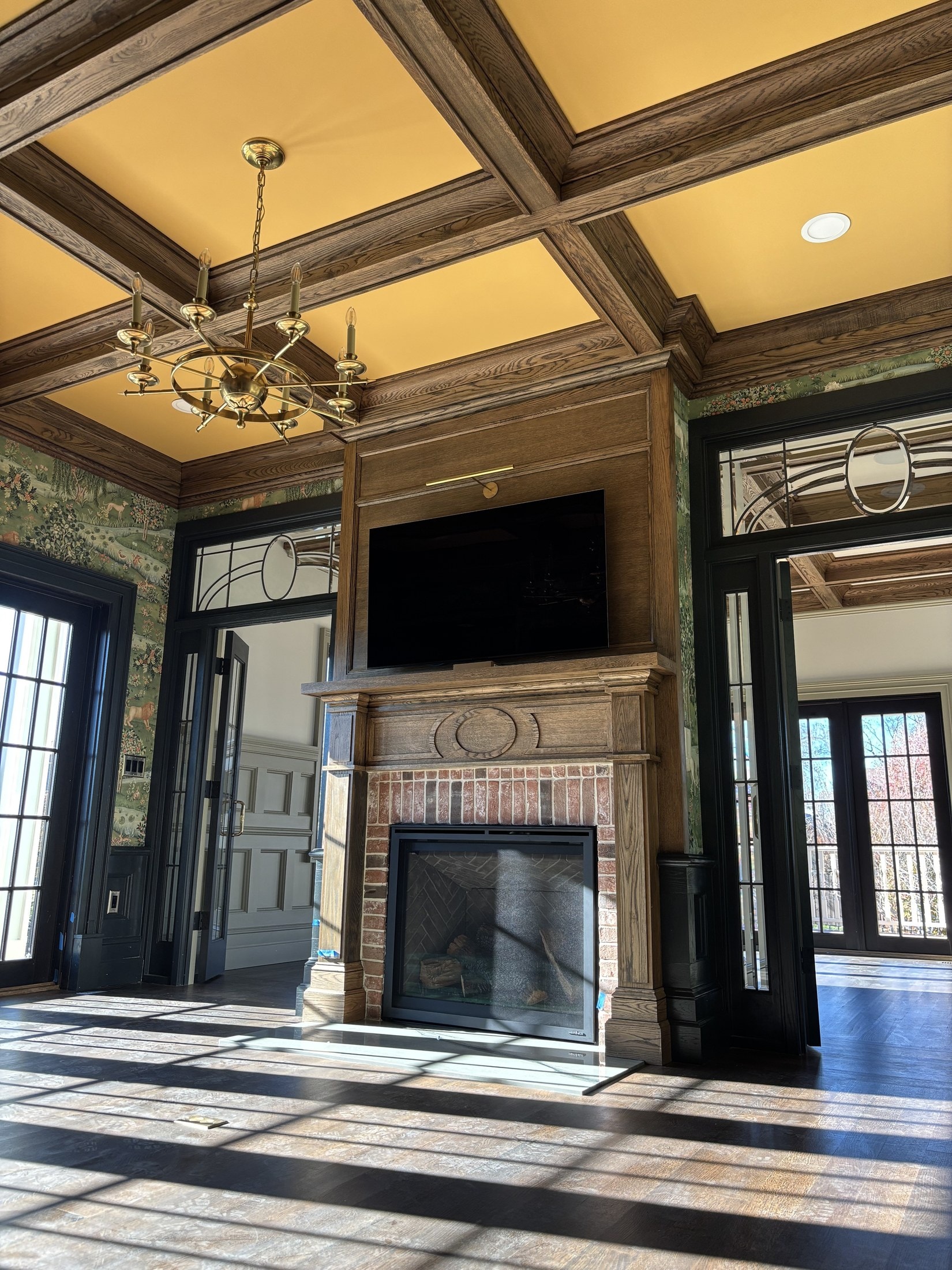 Great room with coffered ceiling, oak beams, paneling, and a brick fireplace