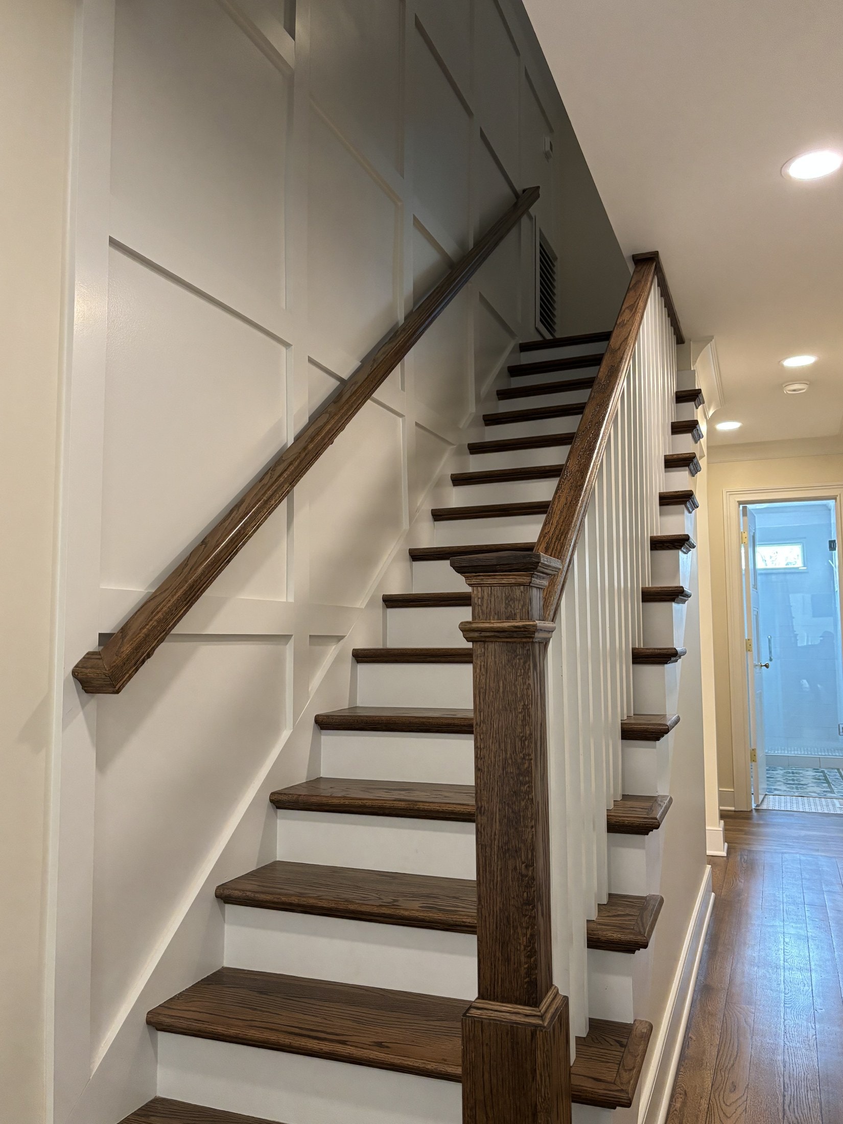 Stained oak handrail and balusters over picture-frame wainscoting on a stair landing